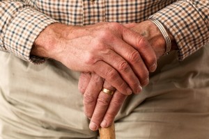 hands of elderly man with wedding ring, holding a cane
